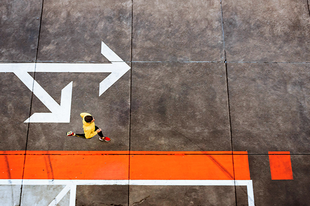 An man jogging through the streets with arrows and paint markings on the concrete