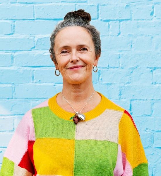 middle aged woman smiling wearing a colorful block sweater