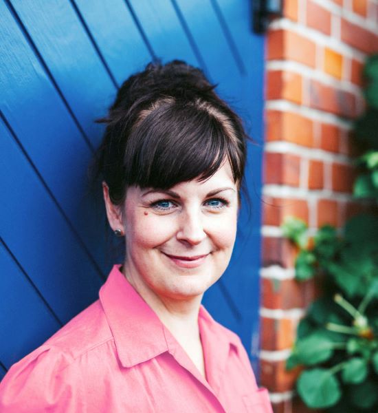 portrait of a middle aged woman smiling wearing a pink button down shirt