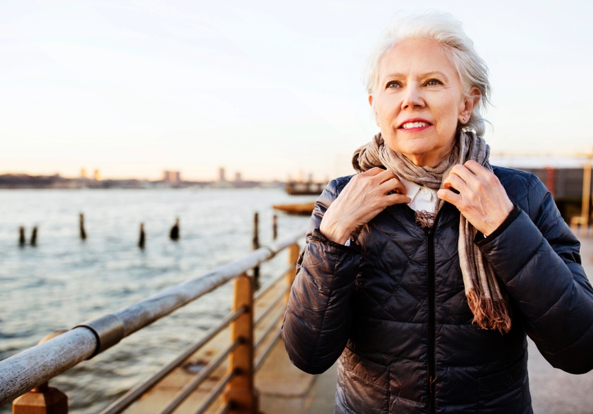 An older woman stands by the water, symbolizing the dignity and fulfillment of a secure retirement