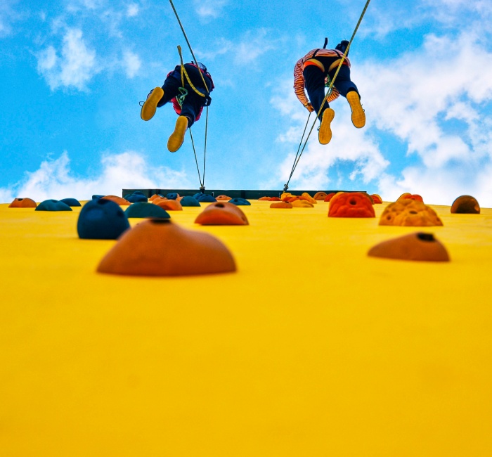 Two people scale a climbing wall, symbolizing the journey of retirement savings and the significance of making financial planning accessible